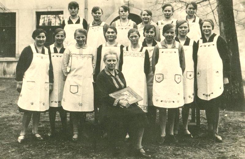 Die Mädchen lernen von Frau Heilmann mit dem 'Großen Lehrbuch der Wäsche', wie man einen Haushalt führt.